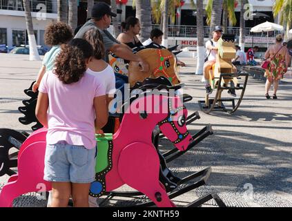 Puerto Vallarta, Mexiko - 9. November 2022 - Besucher genießen das öffentliche Schaukelpferd auf der Straße Stockfoto