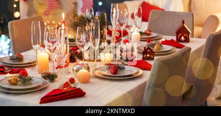 Stilvolle Tischgestaltung mit brennenden Kerzen und Weihnachtsdekorationen im Zimmer Stockfoto