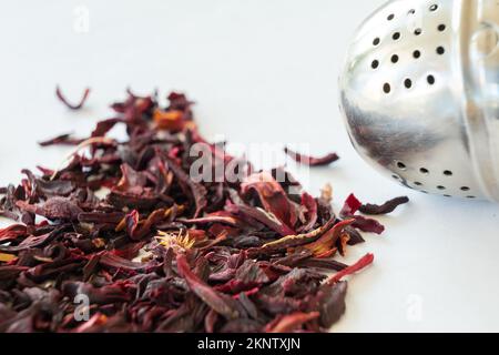 Nahaufnahme von losen Hibiskus-Teeblättern und Teebällen auf weißem Hintergrund. Stockfoto