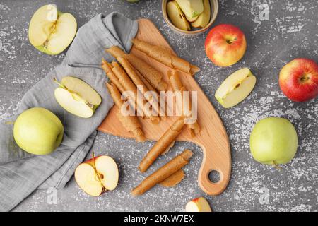 Holzbrett mit leckeren Obstpastillen und frischen Äpfeln auf Grunge-Hintergrund Stockfoto