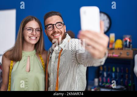 Lächelnde Männer und Frauen machen Selfies per Smartphone in der Bekleidungsfabrik Stockfoto
