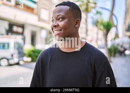 Junge afroamerikanische Transgender lächelt selbstbewusst auf der Straße Stockfoto