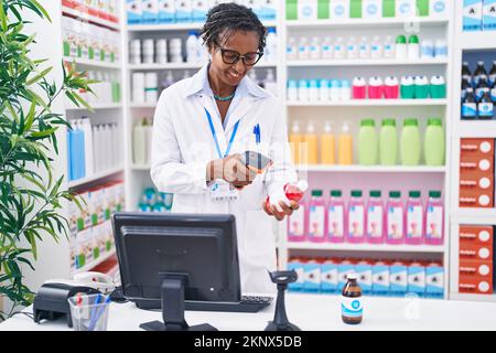 afroamerikanerin mittleren Alters, apotheke, die Pillen scannt, in der Apotheke Stockfoto