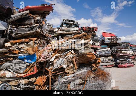 Gestapelte und zerstoßene Autos auf dem Altmetall-Recyclingplatz. Stockfoto