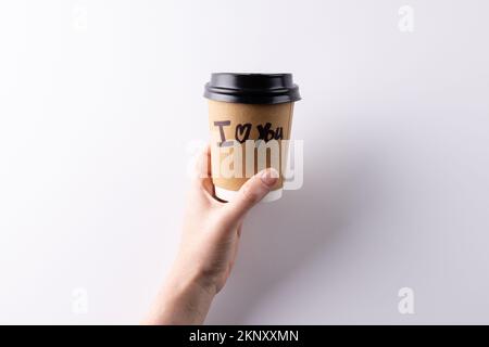 Hand halten Kaffeetasse zum Mitnehmen mit "ich liebe dich", du schreibst darauf, mit Kopierraum Stockfoto