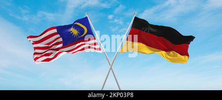 Zwei gekreuzte Flaggen Bundesrepublik Deutschland und Malaysia, die im Wind am bewölkten Himmel winken. Beziehungskonzept, Dialog, Reisen zwischen zwei Zählungen Stockfoto