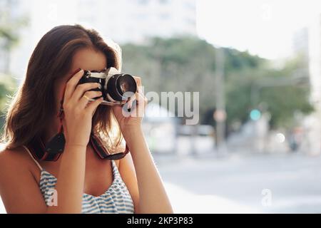 Ich genieße ihre neue Kamera. Eine attraktive junge Frau in einer städtischen Umgebung. Stockfoto