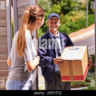 Es kommt immer pünktlich an. Ein Kurier, der eine Lieferung an einen lächelnden Kunden macht. Stockfoto