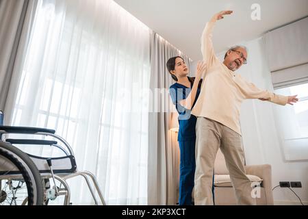 Der alte Senior-Mann trainiert zu Hause gern mit einem Physiotherapeuten für ausgestreckte Arme Stockfoto