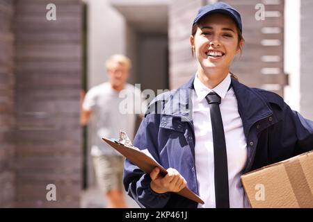 Es kommt immer pünktlich an. Ein Kurier, der eine Lieferung an einen lächelnden Kunden macht. Stockfoto