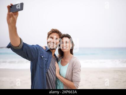 Aufnahmen vom Paradies. Ein junges Paar, das sich am Strand fotografiert. Stockfoto