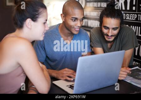 Brainstorming über den neuesten Blog. Eine Gruppe von Freunden, die einen Laptop in einem Café verwenden. Stockfoto