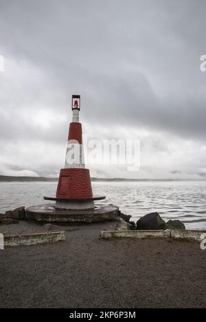 Ein Beachy Head Lighthouse in der Ferne mitten im Meer mit bewölktem Himmel, Großbritannien, vertikale Aufnahme Stockfoto