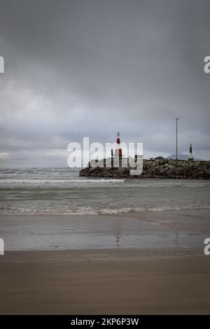 Ein Beachy Head Lighthouse in der Ferne mitten im Meer mit bewölktem Himmel, Großbritannien, vertikale Aufnahme Stockfoto