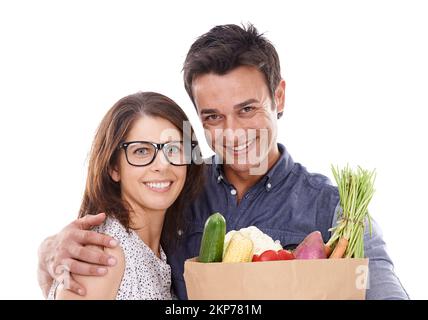 Nur das Beste für uns. Studioporträt eines Paares mit Lebensmitteln isoliert auf weiß. Stockfoto