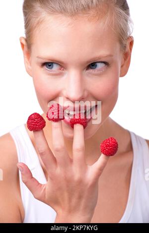 Fingerfood. Eine schöne junge Frau, die Himbeeren von ihren Fingerspitzen isst. Stockfoto