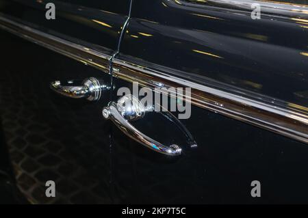 Verchromte Griffe an der Tür eines schwarzen Retro-Autos Stockfoto