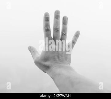 Die Hand eines Mannes zeigt fünf Finger im Nebel. Mystisches Konzept Stockfoto