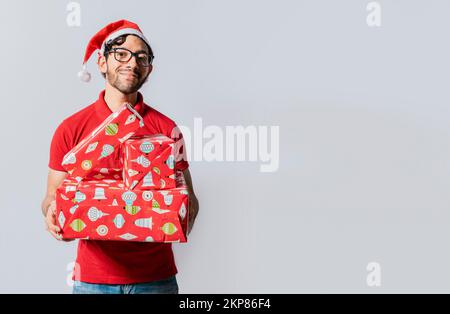 Weihnachtsmann Porträt mit Geschenkschachteln und Lächeln isoliert. Ein lächelnder Typ mit weihnachtsmannmütze, der Weihnachtsgeschenke in der Hand hat. Ein freundlicher Mann im weihnachtsschmuck Stockfoto