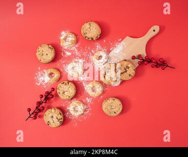 Kreatives Weihnachtsessen-Konzept mit süßen hausgemachten Plätzchen, flach auf rotem Hintergrund. Ein schönes, köstliches Neujahrsgeschenk für die ganze glückliche Familie. Stockfoto