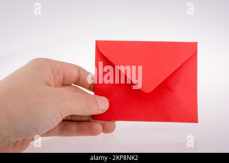 Hand mit einem roten Umschlag auf Weiß Stockfoto