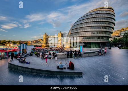 Zuschauer im Scoop Amphitheater mit London City Hall und Tower Bridge über der Themse in der Abendsonne, London, City of London, England, vereinen sich Stockfoto