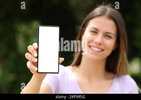 Glücklicher Teenager, der in einem Park einen leeren Smartphone-Bildschirm zeigt Stockfoto