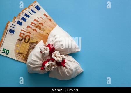Euro-Banknoten und Münztaschen auf blauem Hintergrund. Wirtschafts-, Finanz- und Wechselkurskonzept Stockfoto