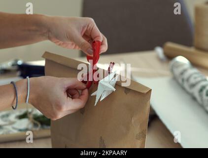 Eine Frau, die ein verpacktes weihnachtsgeschenk dekoriert. Stockfoto