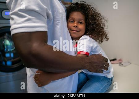 Kind umarmt ihren Vater in der Wäscherei Stockfoto