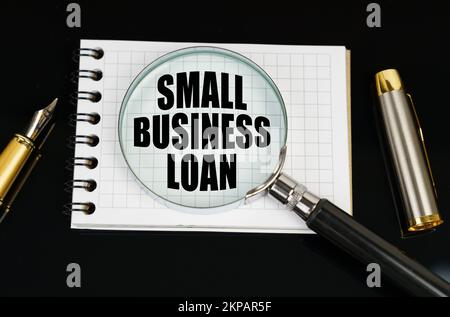 Geschäfts- und Finanzkonzept. Auf einer schwarzen Oberfläche befinden sich ein Stift, ein Notizbuch und eine Lupe. Die Aufschrift auf dem Notizbuch – SMALL BUSINESS L Stockfoto