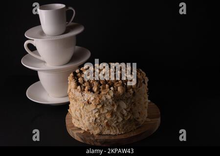 Fotokuchen mit Tellern, Löffel, Untertassen, die in einer vertikalen Reihe auf schwarzem Hintergrund gestapelt sind Stockfoto