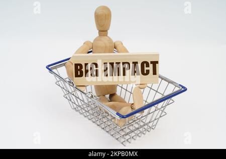 Geschäfts- und Finanzkonzept. Ein Mann aus Holz sitzt in einem Warenkorb und hält ein Schild in den Händen - Big Impact Stockfoto