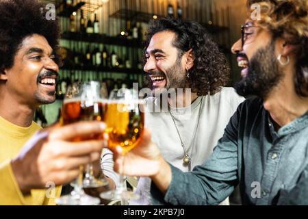 Fröhliche multirassische Freunde, die Bier in der Bar trinken Stockfoto