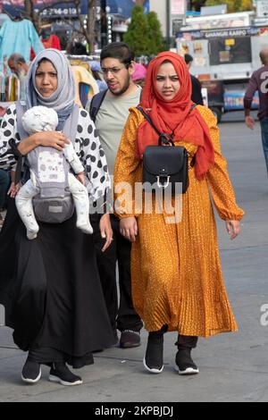 Frauen in Hijabs, eine mit einem Kind, laufen in einem milden Herbst durch Diversity Plaza. InJackson Heights, Queens New York City. Stockfoto