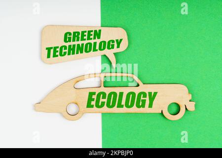 Umweltkonzept. Auf weißem und grünem Hintergrund eine hölzerne Figur eines Autos mit der Inschrift „Ecology“ und ein Schild mit der Inschrift „Green“ Stockfoto