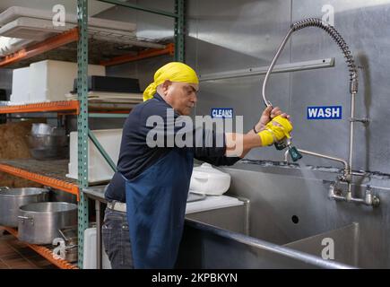 Ein Sikh-Mann mittleren Alters, der freiwillig in der Langar Gemeinschaftsküche im Keller seines Tempels arbeitet. Richmond Hill Queens, New York. Stockfoto