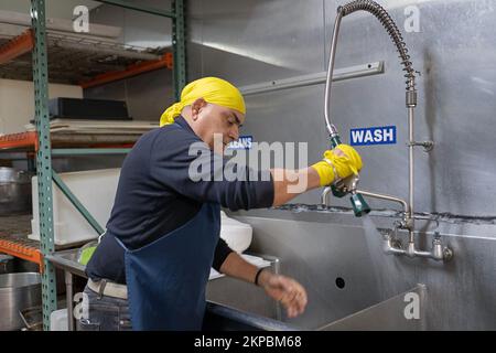 Ein Sikh-Mann mittleren Alters, der freiwillig in der Langar Gemeinschaftsküche im Keller seines Tempels arbeitet. Richmond Hill Queens, New York. Stockfoto