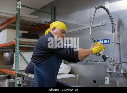 Ein Sikh-Mann mittleren Alters, der freiwillig in der Langar Gemeinschaftsküche im Keller seines Tempels arbeitet. Richmond Hill Queens, New York. Stockfoto