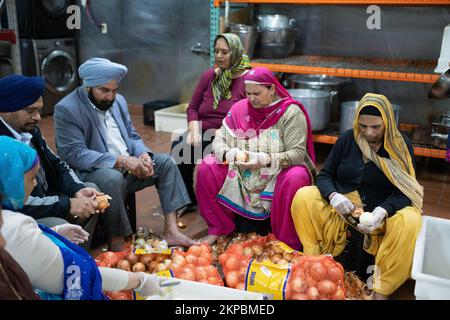 Freiwillige schälen Zwiebeln auf einer Sikh Temple Langar als Teil der kostenlosen Mahlzeiten, die Gläubigen, Besuchern und Gästen angeboten werden. In Queens, New York. Stockfoto