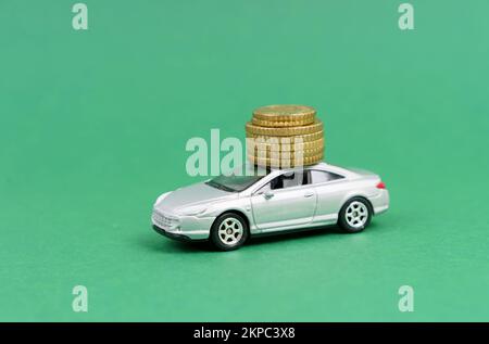 Geschäfts- und Finanzkonzept. Auf grünem Hintergrund befindet sich ein Spielzeugauto, auf dem sich auch Münzen befinden. Stockfoto