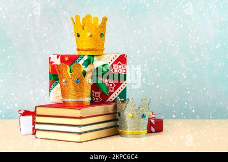Drei Kronen der drei Weisen mit Büchern, geschenkschachteln und Schneeflocken auf blauem Hintergrund Stockfoto