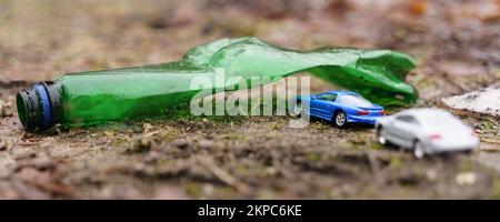 Umweltkonzept. Die Leute fahren im Urlaub mit ihren Autos durch einen Bogen aus einer Plastikflasche - ein Symbol der Verschmutzung. Stockfoto