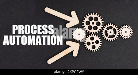 Industriekonzept. Auf der schwarzen Oberfläche, Pfeile, Zahnräder und eine Aufschrift - PROZESSAUTOMATISIERUNG Stockfoto