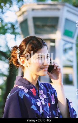 Eine Japanerin in Yukata, die telefoniert Stockfoto