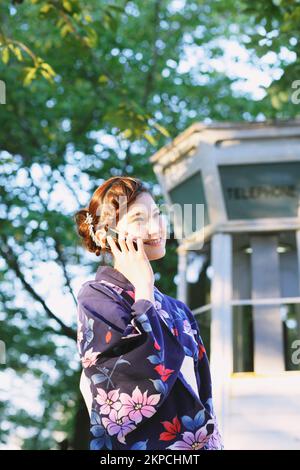 Eine Japanerin in Yukata, die telefoniert Stockfoto