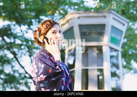 Eine Japanerin in Yukata, die telefoniert Stockfoto