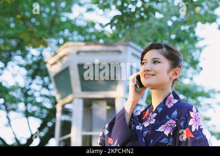 Eine Japanerin in Yukata, die telefoniert Stockfoto