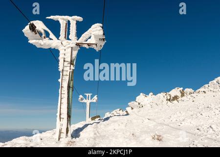 Alte rostige, ausgediente Sesselliftmasten bedeckt mit Schnee und Reimeis auf dem Vitosha-Berg oberhalb von Sofia, Bulgarien bei sonnigem Wetter mit Kopierraum Stockfoto