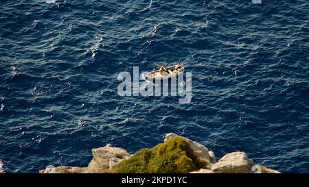 Frachtschiff auf See. Transitschiff. Segelboote. Fischerboot. Angeln. Besichtigungsboot. Boot, Schiff schwimmt in blauem Wasser. Sonnenbrand und Schiffsreflexion Stockfoto